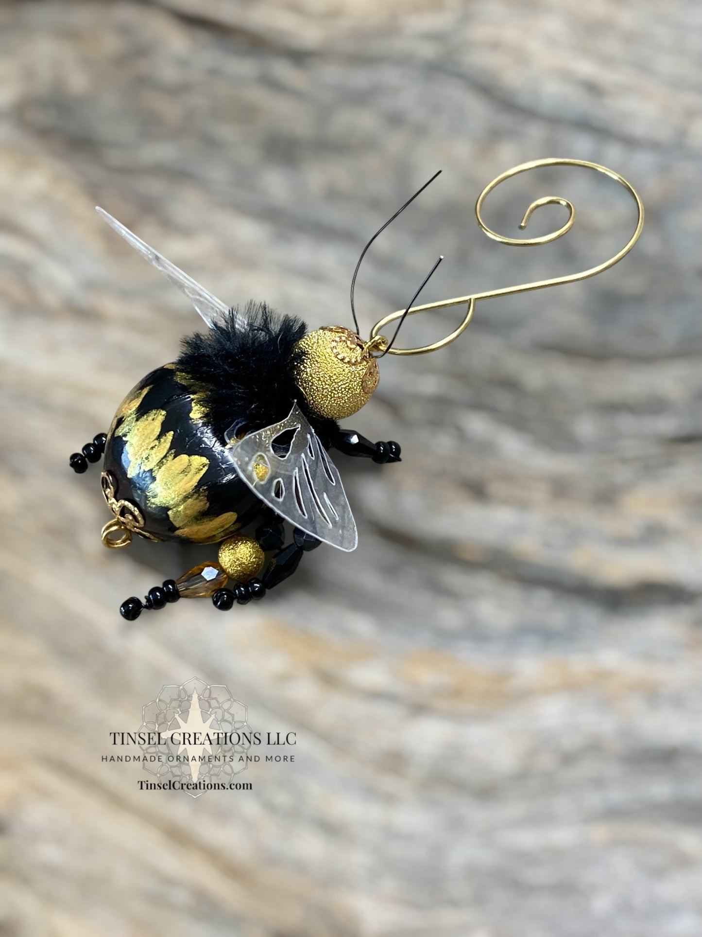 Decorative bee ornament with gold and black details on a textured surface