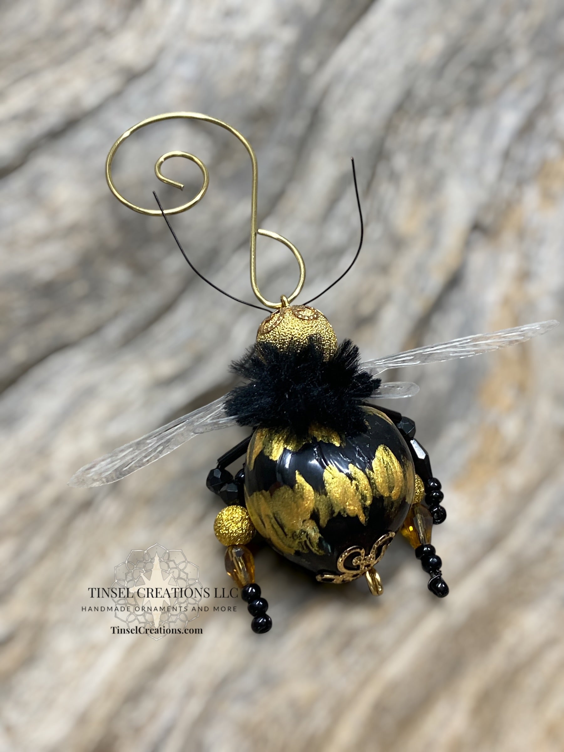 Decorative bee ornament with gold and black details on a wooden surface