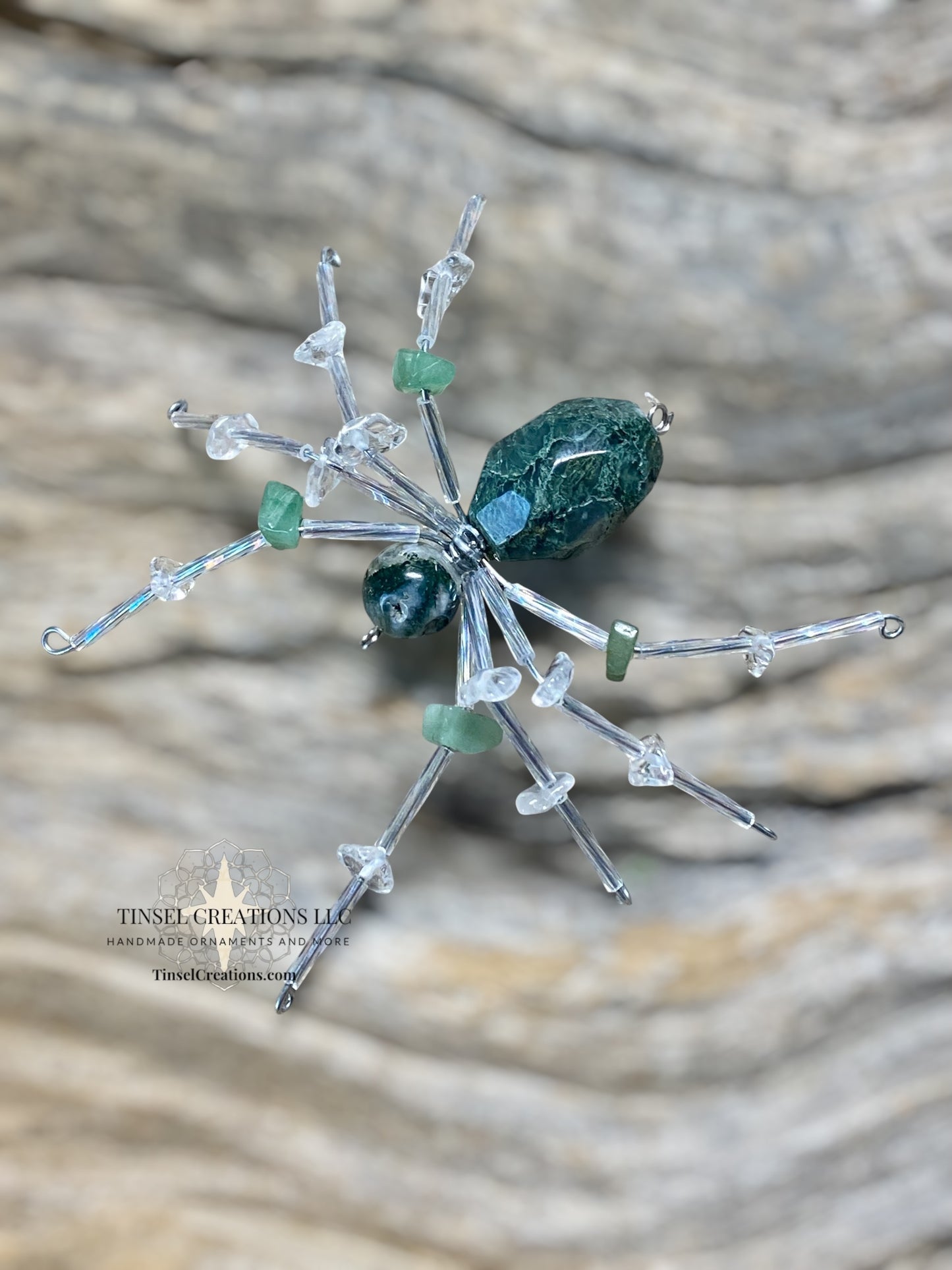 Decorative spider with green and clear elements on a textured surface
