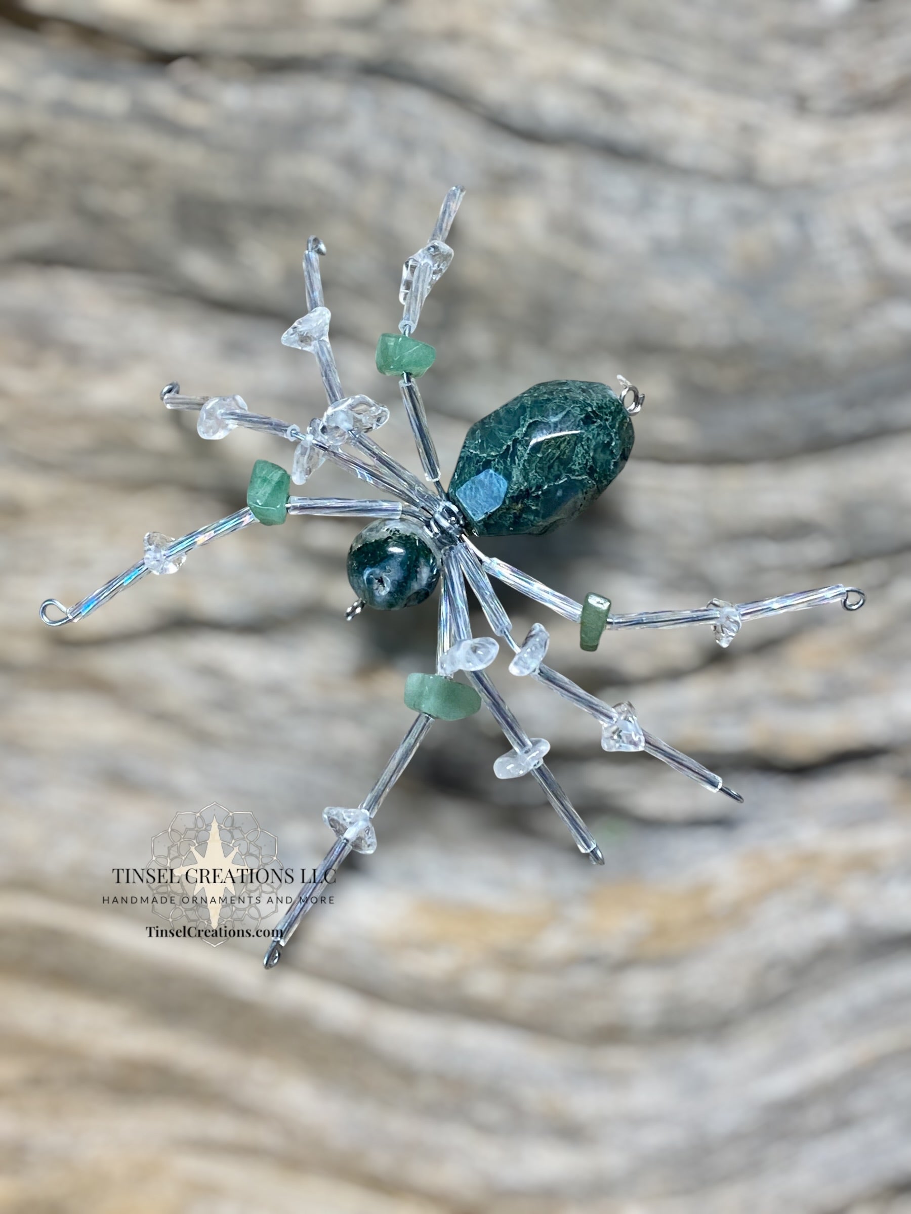 Decorative spider with green and clear elements on a textured surface