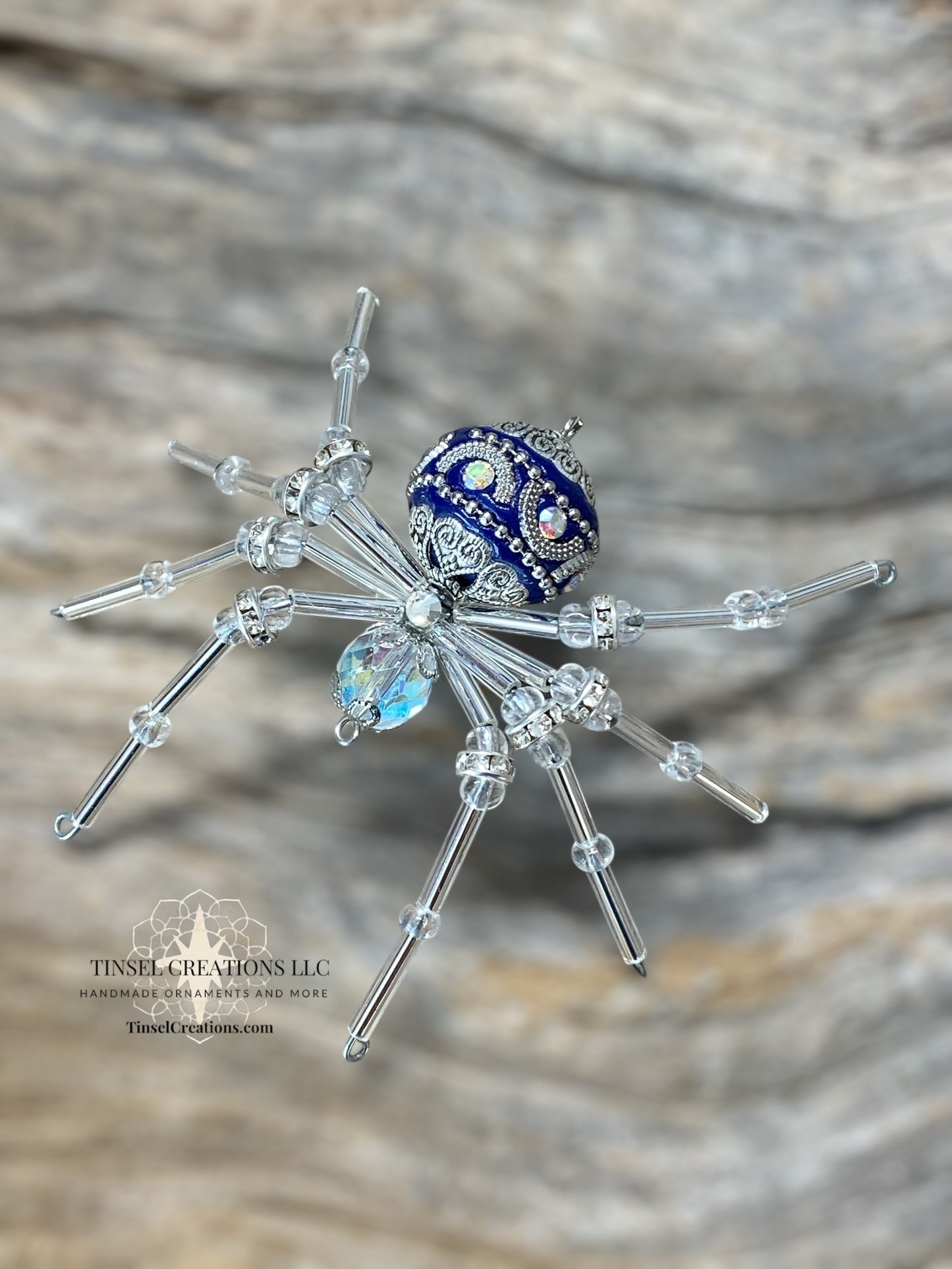 Decorative spider with blue and silver accents on a wooden surface