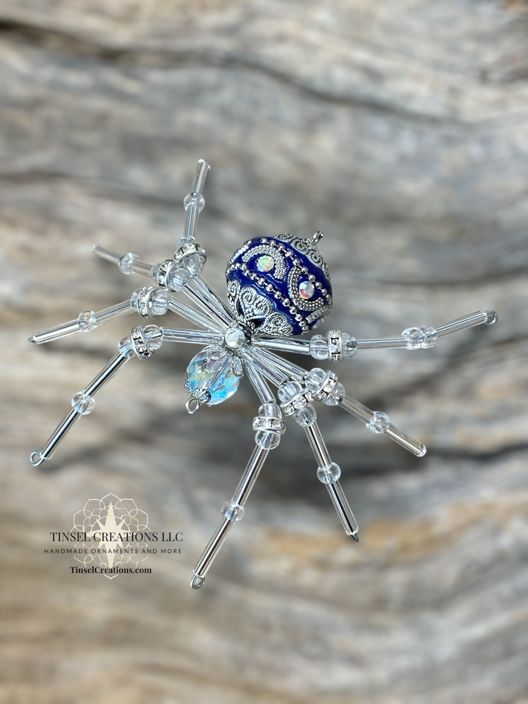 Decorative spider with blue and silver accents on a wooden surface