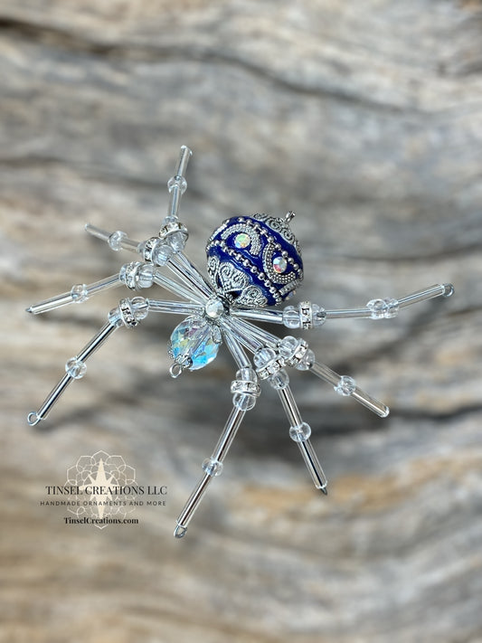Decorative spider with blue and silver accents on a wooden surface