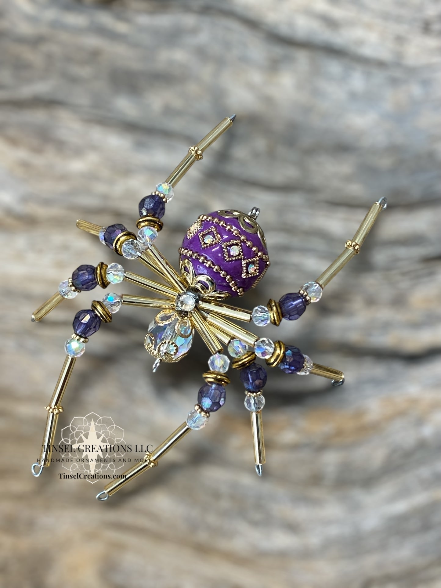 Decorative spider with purple center and gold legs on a textured surface