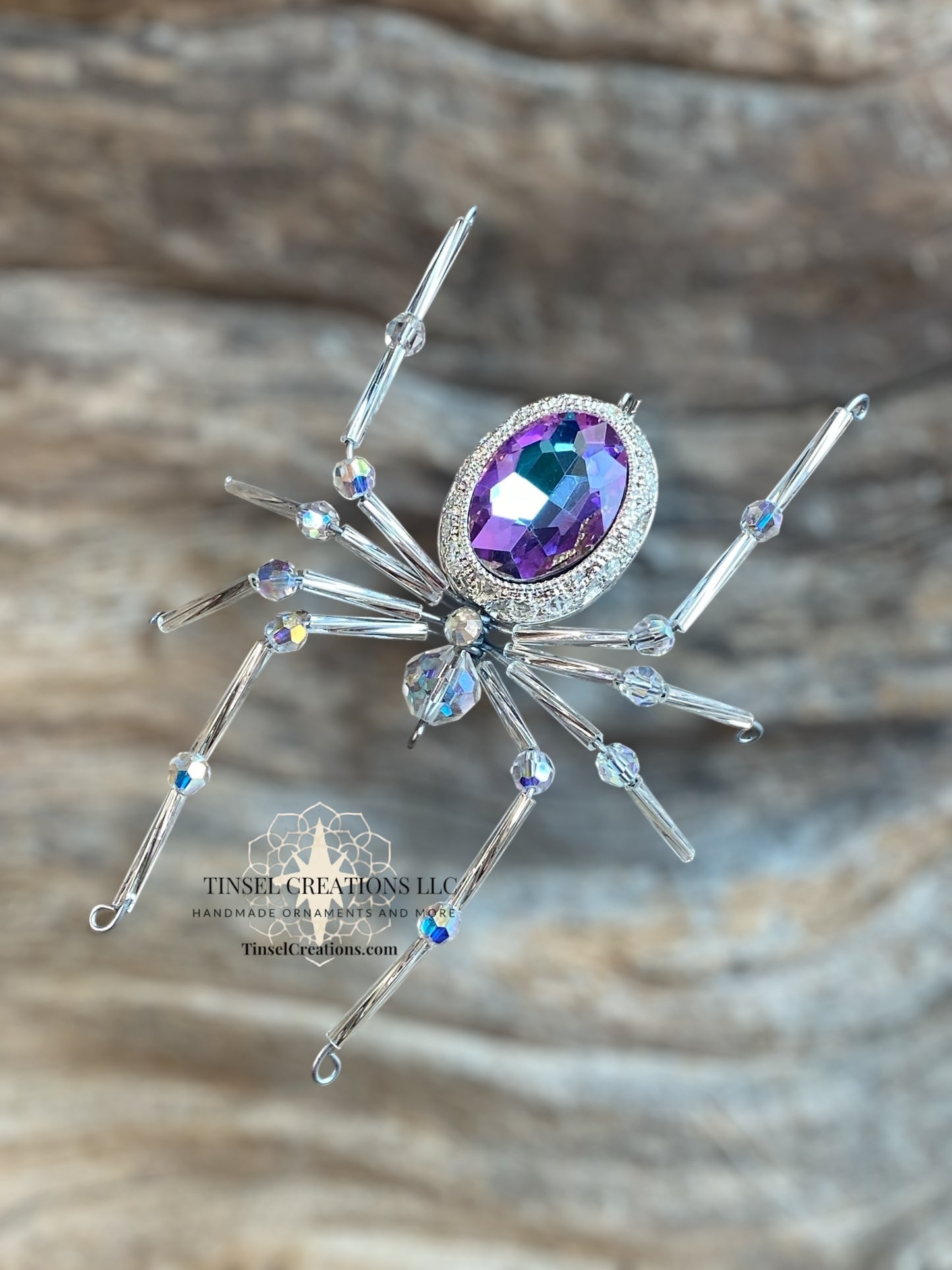 Decorative spider with a purple gemstone on a wooden background