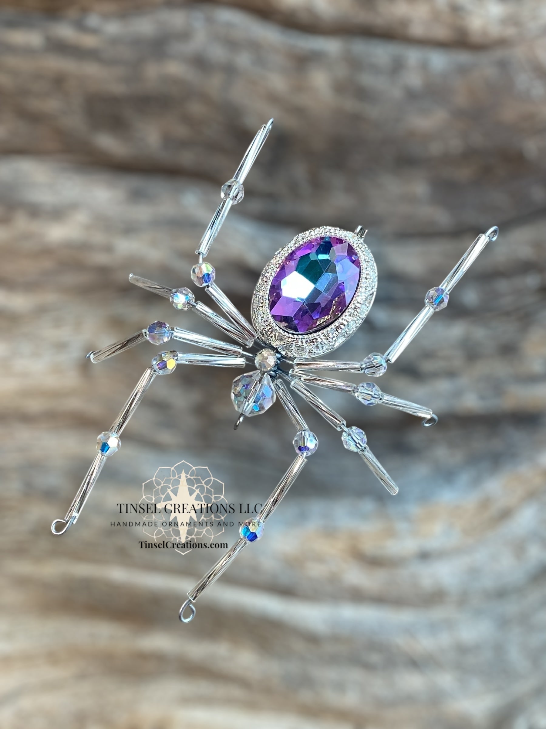 Decorative spider with a purple gemstone on a wooden background