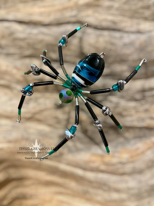 Decorative spider with blue and green accents on a wooden surface