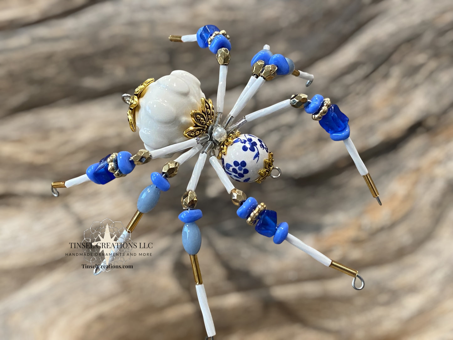 Decorative spider with blue, white, and gold elements on a textured surface
