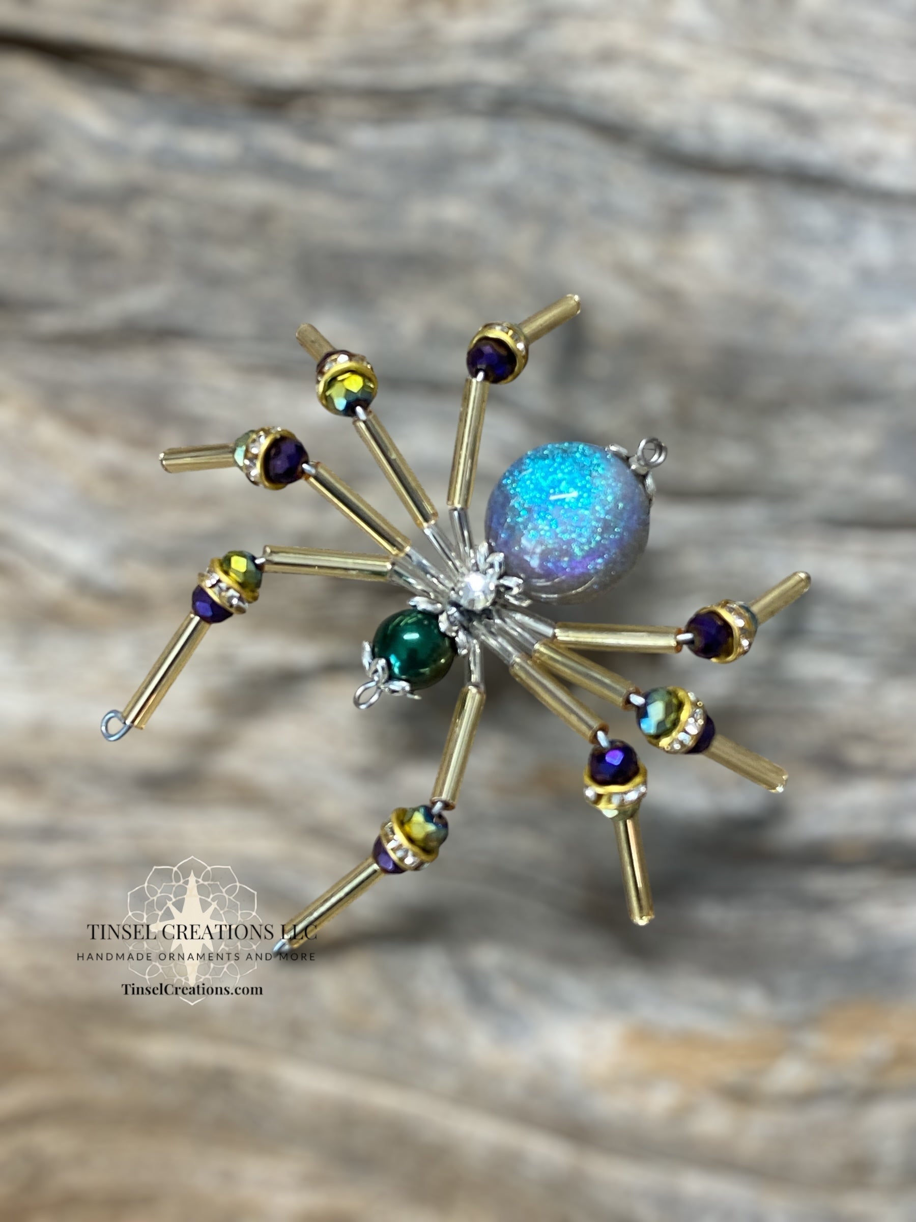 Decorative spider ornament with colorful gemstones on a wooden surface